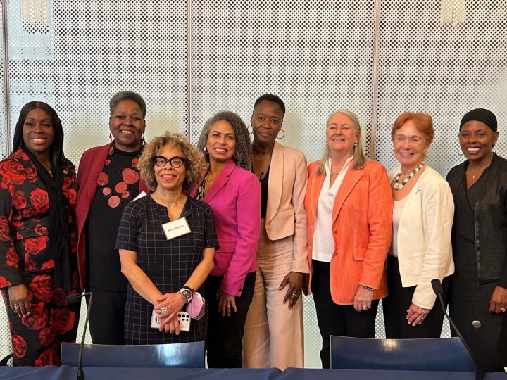 Group of eight speakers stand together at Graham's Women in Leadership Breakfast 2025