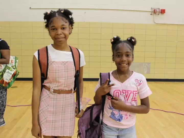 Two girls pose with their new backpacks at a Graham back-to-school event